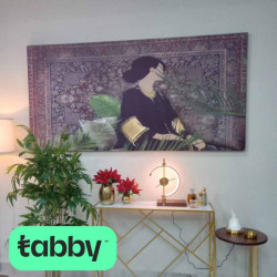 A canvas painting of an oriental girl wearing an abaya sitting on an Arab sofa with a Persian rug behind her